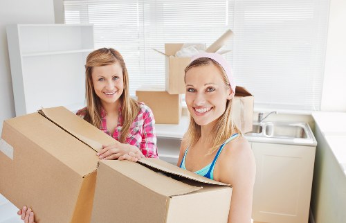 Local removalists carrying household items through a narrow stairwell in Earls Court